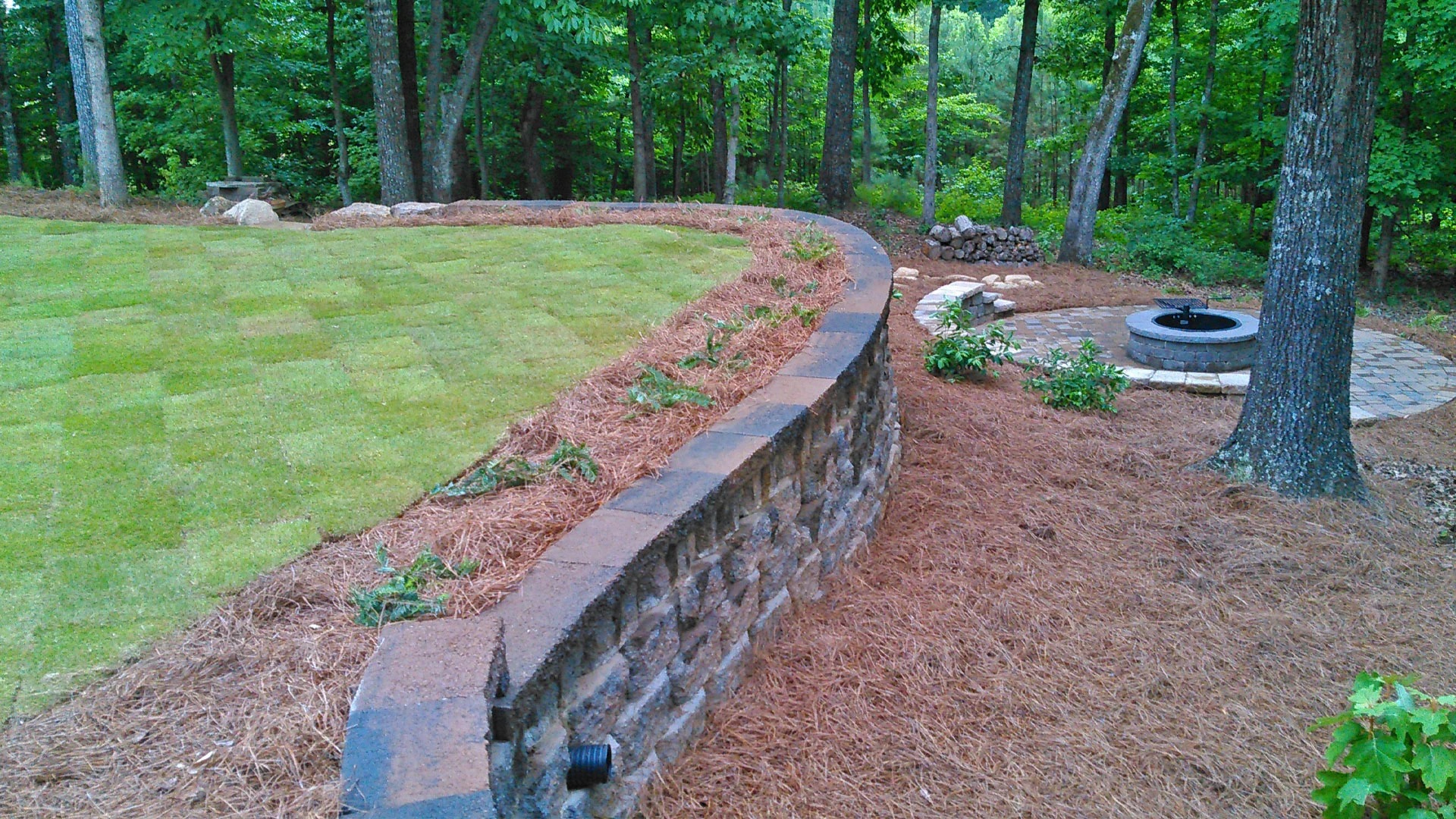 A new fire pit, retaining wall, seating wall, landscaping, and sod installed at a home in Smyrna.