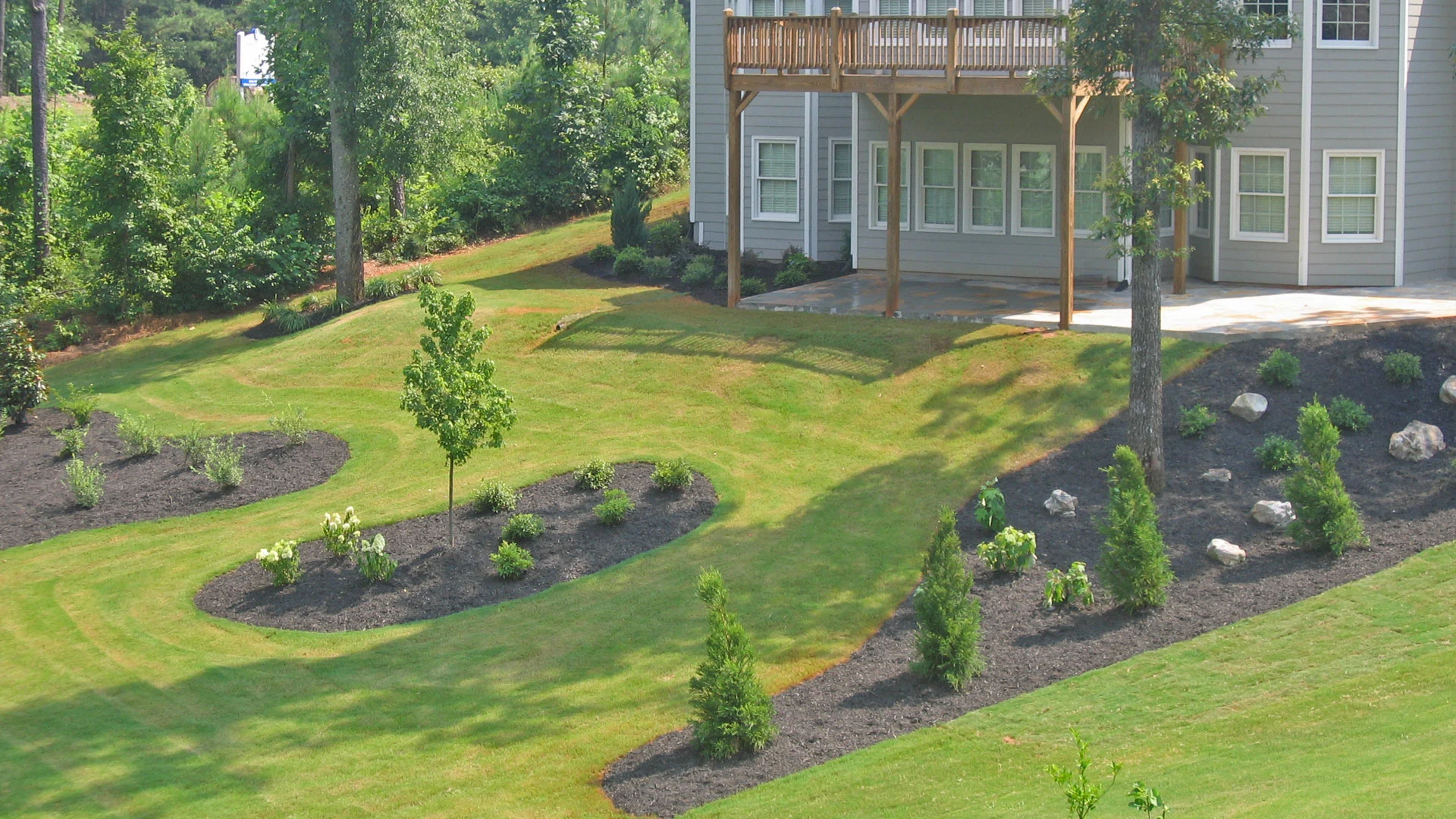 Large back yard with new landscaping beds, plants, and mulch at a home in Buckhead, GA