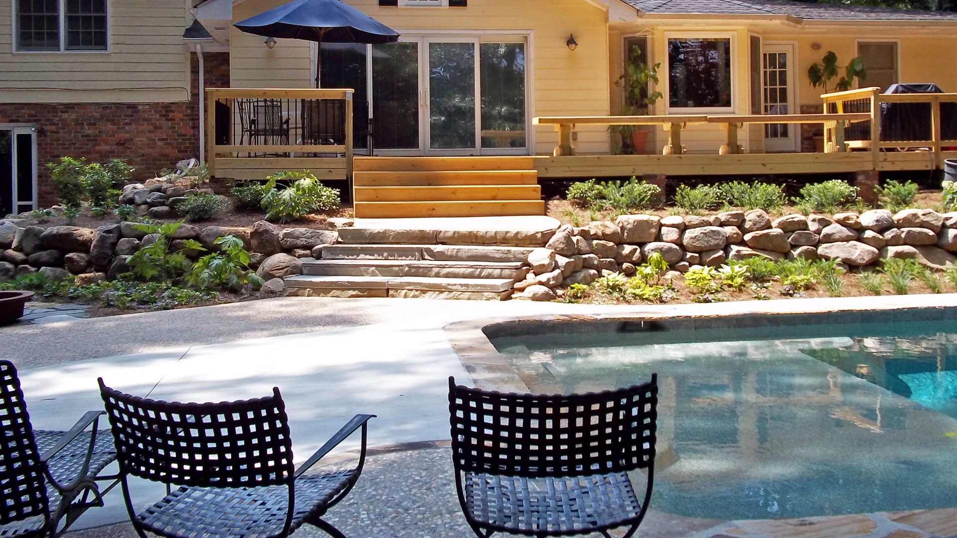 Rock retaining wall with landscaping around a pool at a home in Mableton, GA.