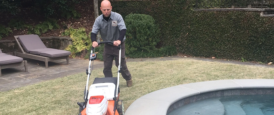 Lawn maintenance technician mowing grass at a home in Buckhead, GA. 