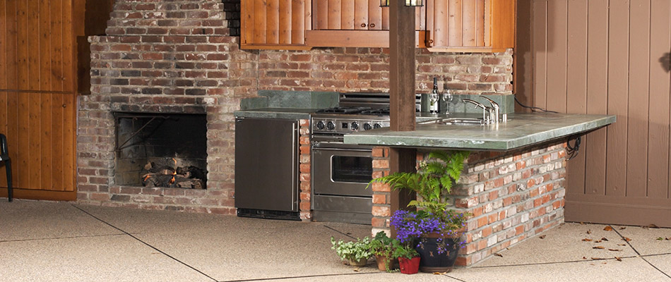 A red brick outdoor kitchen with fireplace at a property in Peachtree Hills, GA.