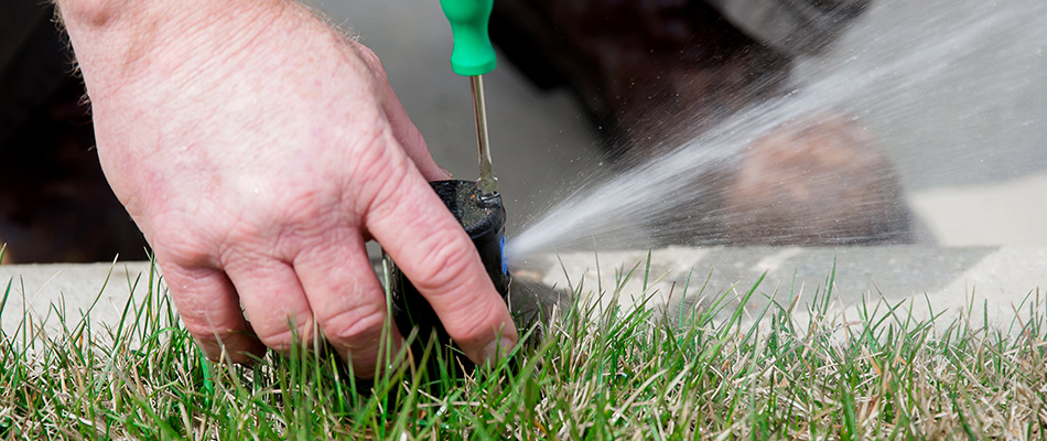 Irrigation technician adjusting sprinkler head in Buckhead, GA. 