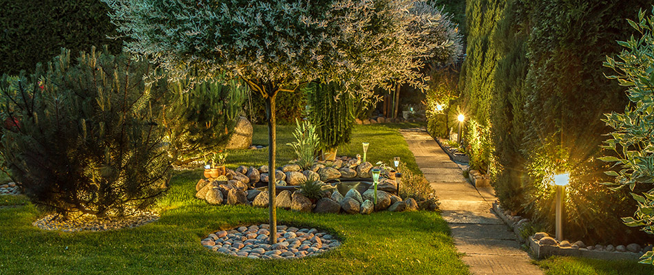 A lit up backyard full of foliage and a paved walkway in Alpharetta, GA.